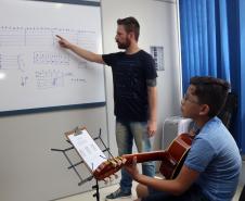 O professor Rodrigo Haniskievicz orienta o aluno Alexandre Pinheiro Neto. Local atende estudantes de música de todas as idades. Empreendedor usou a linha da Fomento Paraná, desenvolvida em parceria com a Secretaria de Estado da Cultura para apoiar empreendimentos da economia criativa.