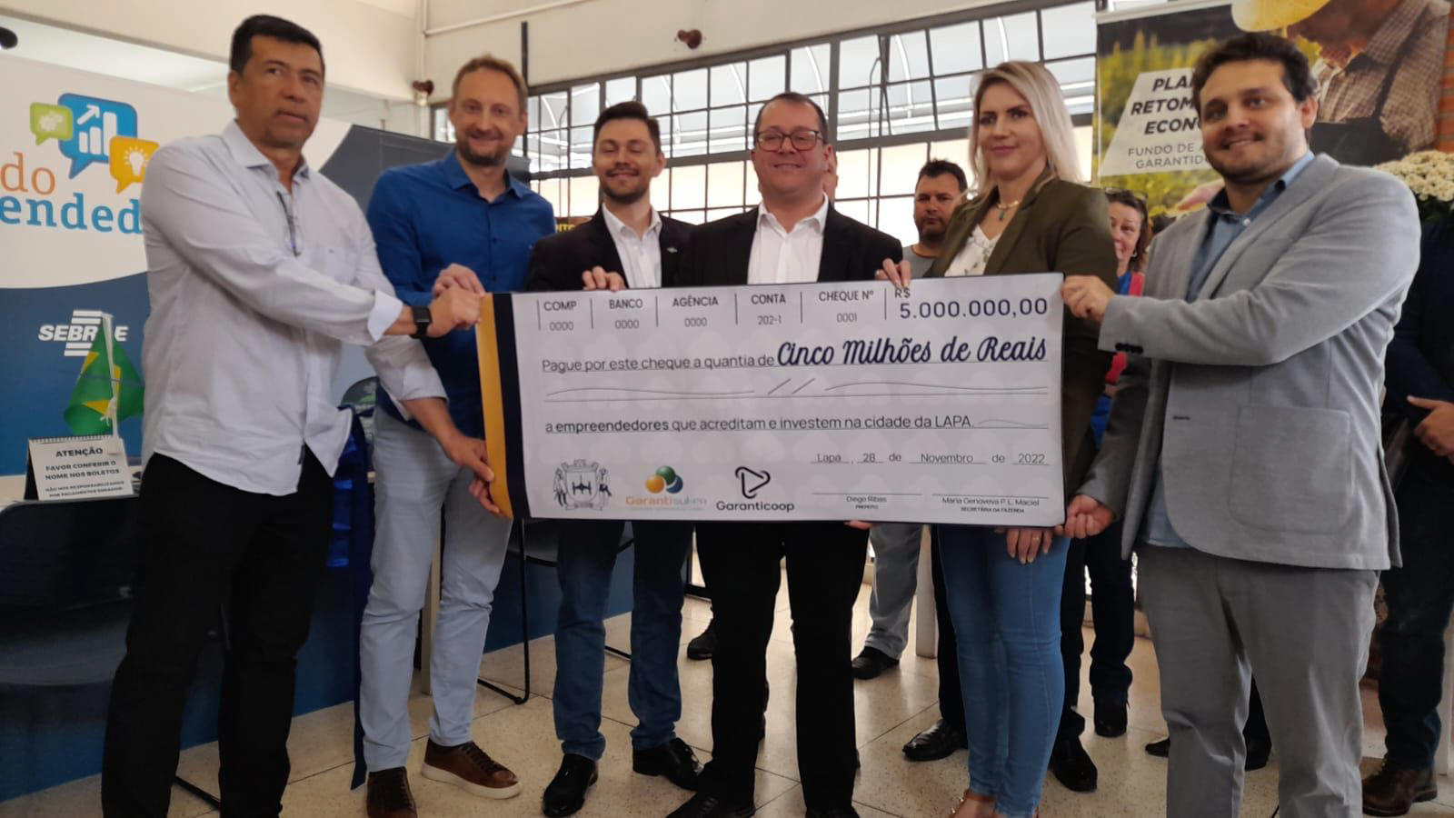 Grupo de pessoas mostra cheque gigante de R$ 5 milhões de reais