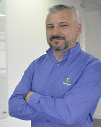 Renato Maçaneiro é um homem branco, tem cabelos curtos, um pouco grisalhos, usa barba, também grizalha nas laterais do rosto. Ele usa uma camisa azul clara, de mangas compridas e com a logomarca da Fomento Paraná no lado esquerdo do peito.