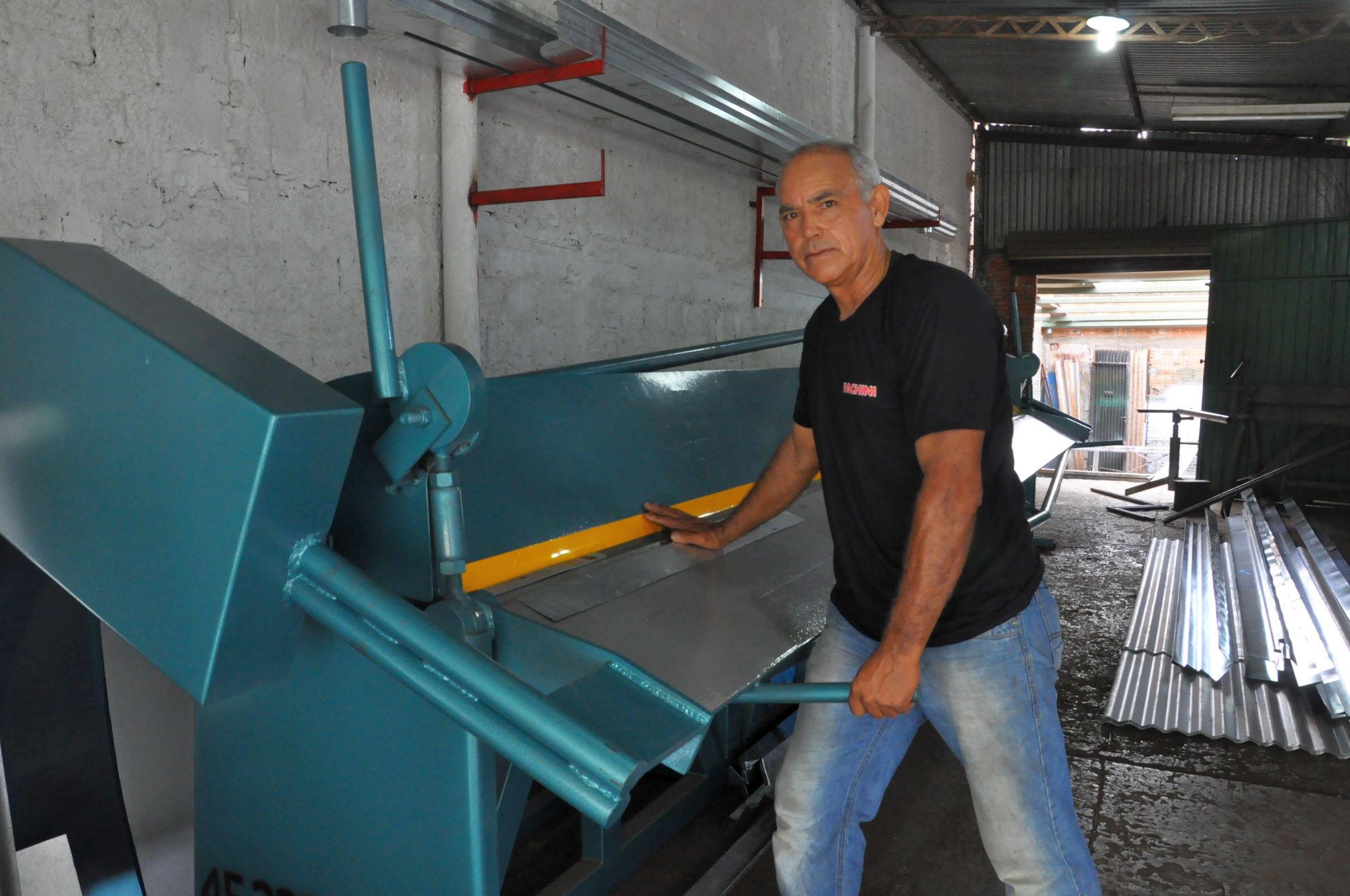 Edilson de Lima, em Foz do Iguaçu, com sua nova máquina de dobrar calhas, comprada com um financiamento de microcrédito da Fomento Paraná.