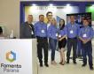 Equipe Fomento Paraná, no atendimento aos empresários e dirigentes de associações comerciais e empresariais. Grupo de seis pessoas, com camisas azuis, em pé, ao lado de um balcão, no estande da Fomento Paraná no evento.