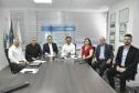 Reunião entre diretores da Fomento paraná e do BDMG em uma sala com uma grande mesa de reuniões