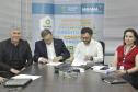 Reunião entre diretores da Fomento paraná e do BDMG em uma sala com uma grande mesa de reuniões. Presidentes da sduas instituições aqssinam documento.