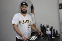 O empreendedor Brendon Oliveira é barbeiro ele usa camiseta branca com a palavra PIRATES e o número 21 estampado. Ele mostra as ferramentas de trabalho e produtos que usa na atividade dele.