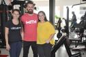 A profissional de educação física buscou financiamento da Fomento Paraná para montar a academia, inaugurada em maio de 2017. Na imagem, com o noivo Thiago Cogo e com a agente de crédito Karoline Hoffmann.