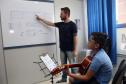O professor Rodrigo Haniskievicz orienta o aluno Alexandre Pinheiro Neto. Local atende estudantes de música de todas as idades. Empreendedor usou a linha da Fomento Paraná, desenvolvida em parceria com a Secretaria de Estado da Cultura para apoiar empreendimentos da economia criativa.