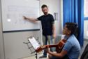 O professor Rodrigo Haniskievicz orienta o aluno Alexandre Pinheiro Neto. Local atende estudantes de música de todas as idades. Empreendedor usou a linha da Fomento Paraná, desenvolvida em parceria com a Secretaria de Estado da Cultura para apoiar empreendimentos da economia criativa.