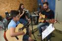 Escola de Palmeira atende estudantes de música de todas as idades. Empreendedor usou a linha da Fomento Paraná, desenvolvida em parceria com a Secretaria de Estado da Cultura para apoiar empreendimentos da economia criativa. Na imagem, os alunos Alexandre Pinheiro Neto e Paloma de Jesus Cubas com o professor Rodrigo Haniskievicz e Webis Duarte (ao fundo).