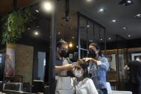 O cabeleireiro Eduardo Bittencourt e a auxiliar dele cuidam do visual de cliente no salão de beleza.