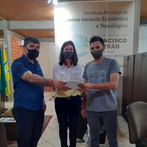 O empreendedor Juliano Cassou Ecker, à direita, assina contrato, na presença do o secretário municipal de Desenvolvimento Econômico de Francisco Beltrão, Inácio Pereira, e a agente de crédito Luciana Dani.