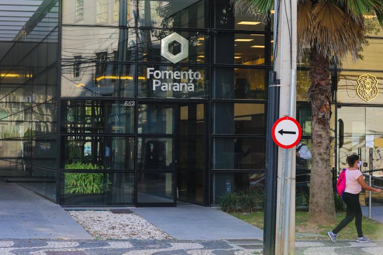 Fachada da Fomento Paraná, toda em vidro fumê, com logotipo metálico prateado