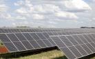 imagem de uma área com muitos painéis solares para produção de energia em um dia ensolarado, mas com nuvens no céu