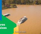 Imagem aérea de dois barcos turisticos navegando em um trecho de rio. à esqueda, sobre um fundo em grafismo verde aparede o texto juros baixos e embaixo uma legenda do audio escrito "cada vez mais"