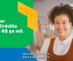 Tela com moça de cabelos cacheados sorrindo à direita e à esquerda um texto em branco sobre um fundo em grafismo verde escrito Valor do Crédito até R$ 50 mil. Uma legenda embaxo diz "para dar uma força para o seu negócio".