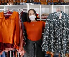 A empresária Josiane Duarte, proprietária de uma loja de roupas para o público evangélico, em Piraquara. Na foto ela mostra roupas coloridas e escuras.