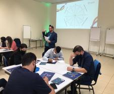 Atividade dinâmica com agentes sentados em mesas durante o Encontro regional de agentes de crédito da Fomento Paraná em Curitiba.