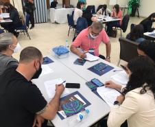 Atividade dinâmica com agentes sentados em mesas durante o Encontro regional de agentes de crédito da Fomento Paraná em Curitiba.