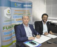 Jorge Callado, do Ipardes, e Heraldo Neves, da Fomento Paraná, assinam documento de entrega do estudo que mediu impacto do crédito na economia paranaense