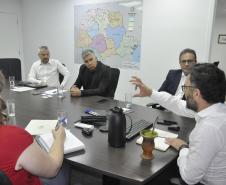 Reunião entre diretores da Fomento paraná e do BDMG em uma sala com uma grande mesa de reuniões