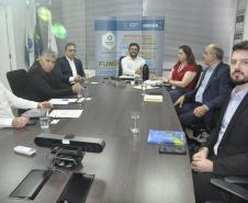 Reunião entre diretores da Fomento paraná e do BDMG em uma sala com uma grande mesa de reuniões