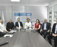 Reunião entre diretores da Fomento paraná e do BDMG em uma sala com uma grande mesa de reuniões