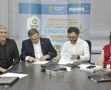 Reunião entre diretores da Fomento paraná e do BDMG em uma sala com uma grande mesa de reuniões. Presidentes da sduas instituições aqssinam documento.