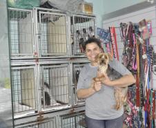 Empreendedora dona de um petshop posa para foto com cãozinho no colo.