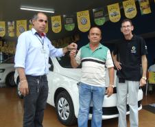 Agente de crédito Reinaldo Ribeiro acompanha os taxistas Estevan Cezar de Oliveira e Rosinei Veronez de Aguiar ao receberem as chaves dos novos veículos.