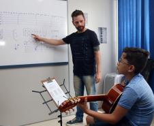 O professor Rodrigo Haniskievicz orienta o aluno Alexandre Pinheiro Neto. Local atende estudantes de música de todas as idades. Empreendedor usou a linha da Fomento Paraná, desenvolvida em parceria com a Secretaria de Estado da Cultura para apoiar empreendimentos da economia criativa.