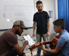 Os professores Rodrigo Haniskievicz (em pé) e Webis Duarte orientam o aluno Alexandre Pinheiro Neto. Local atende estudantes de música de todas as idades. Empreendedor usou a linha da Fomento Paraná, desenvolvida em parceria com a Secretaria de Estado da Cultura para apoiar empreendimentos da economia criativa.