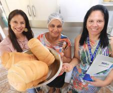 A agente de crédito da Fomento Paraná Eliane Schuback  e a assistente social e coordenadora do Família Paranaense no município de Guaíra, Roselene Evangelista de Assis, com Cleide Pereira Dias, que obteve apoio para financiar a compra de equipamentos para incrementar a renda com a produção de pães caseiros em Guaíra.