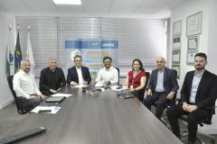 Reunião entre diretores da Fomento paraná e do BDMG em uma sala com uma grande mesa de reuniões