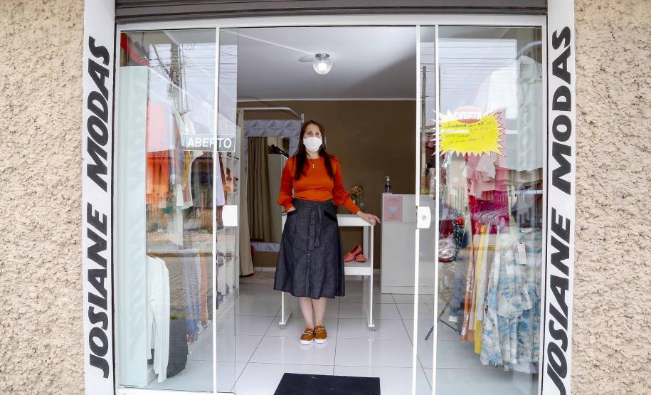 empresária Josiane Duarte, proprietária de uma loja de roupas para o público evangélico, em Piraquara. Na foto ela está dentro da loja, que é uma vitrine com porta no meio, e dá para ver as roupas na loja.