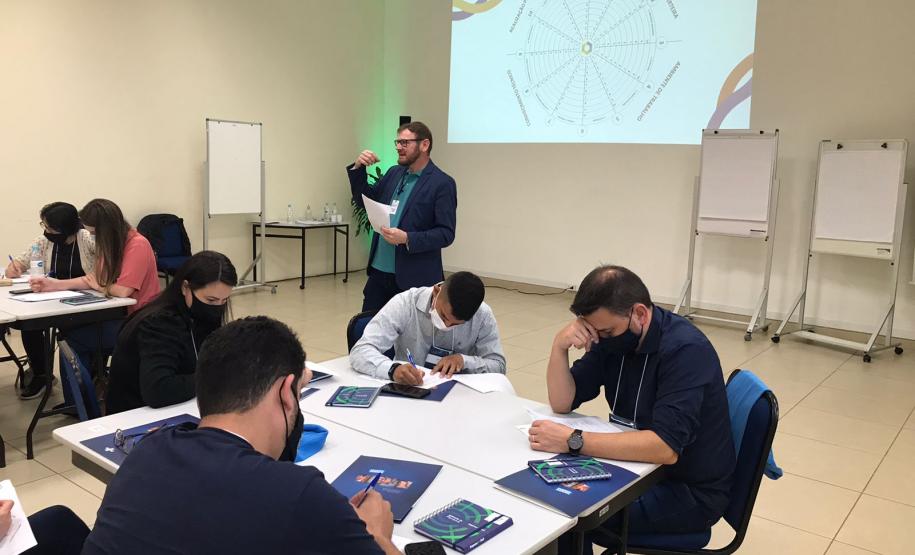 Atividade dinâmica com agentes sentados em mesas durante o Encontro regional de agentes de crédito da Fomento Paraná em Curitiba.