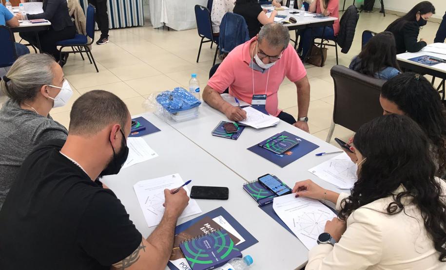 Atividade dinâmica com agentes sentados em mesas durante o Encontro regional de agentes de crédito da Fomento Paraná em Curitiba.