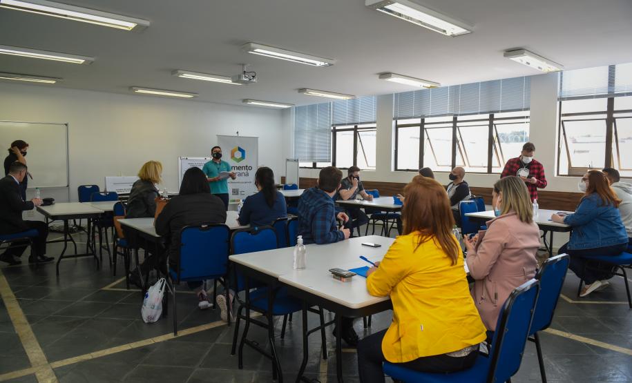 Encontro de agentes de crédito em Curitiba. Pessoas sentadas em grupos ouvem palestra