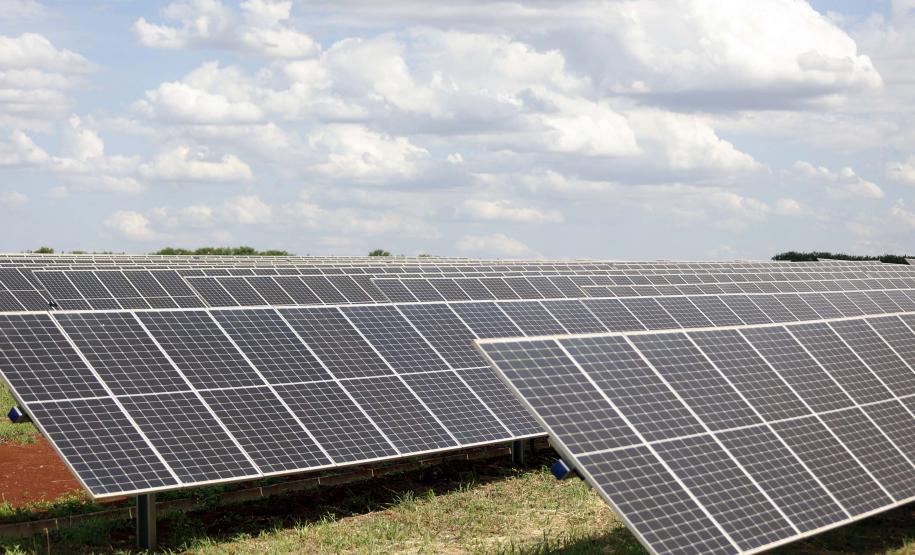 imagem de uma área com muitos painéis solares para produção de energia em um dia ensolarado, mas com nuvens no céu