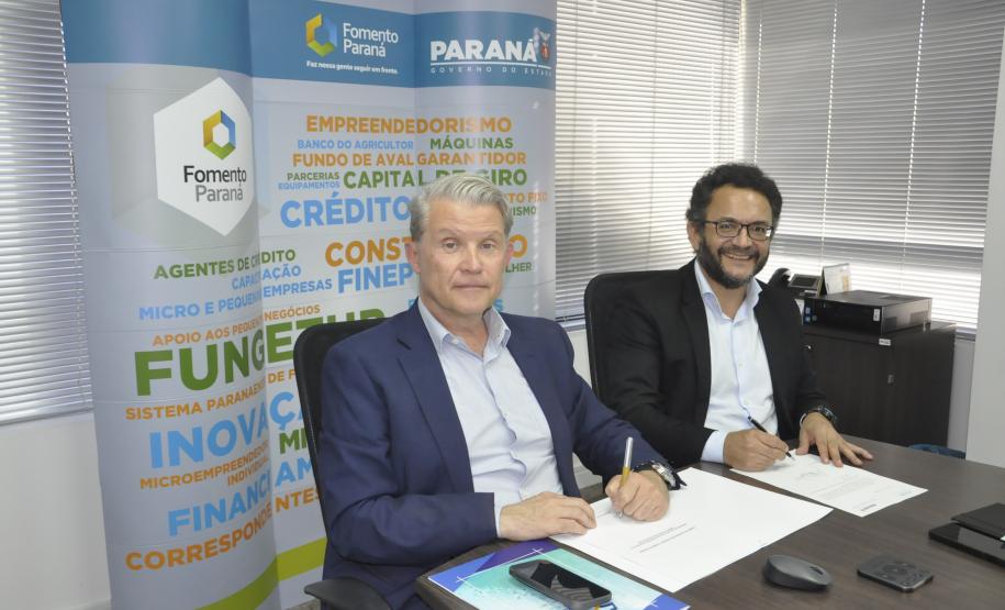 Jorge Callado, do Ipardes, e Heraldo Neves, da Fomento Paraná, assinam documento de entrega do estudo que mediu impacto do crédito na economia paranaense