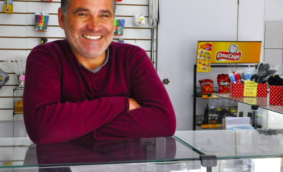 Na imagem, vemos o empreendedor Sandro Silva em sua LanHouse. Sandro é um jovem senhor branco. Na foto, ele usa uma blusa vermelha.