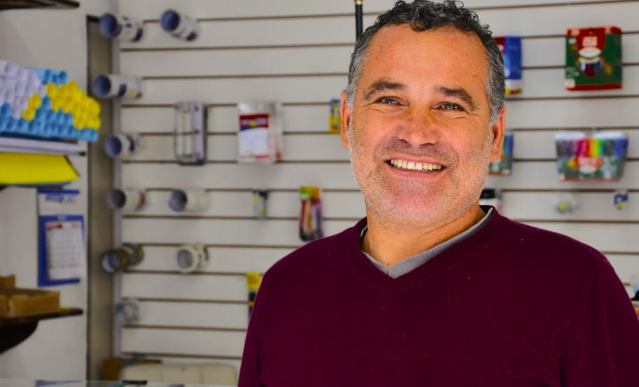 Na imagem, vemos o empreendedor Sandro Silva em sua LanHouse. Sandro é um jovem senhor branco. Na foto, ele usa uma blusa vermelha.