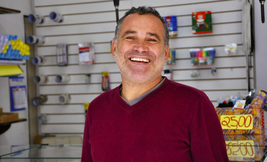 Na imagem, vemos o empreendedor Sandro Silva em sua LanHouse. Sandro é um jovem senhor branco. Na foto, ele usa uma blusa vermelha.