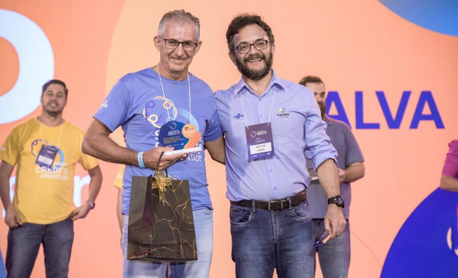 Roberto Carraro, agente de crédito, recebendo premiação do diretor-presidente da Fomento Paraná, Heraldo Neves
