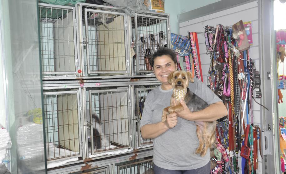 Empreendedora dona de um petshop posa para foto com cãozinho no colo.