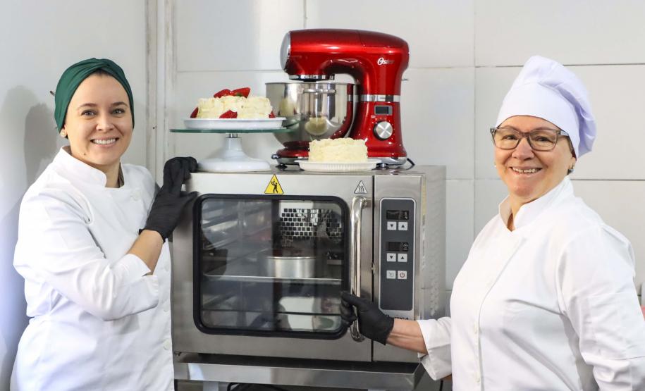 Neusa (à direita), como novo forno e batedeira da empresa familiar adquiridos com financiamento da Fomento Paraná por intermédio da Prefeitura de Curitiba.