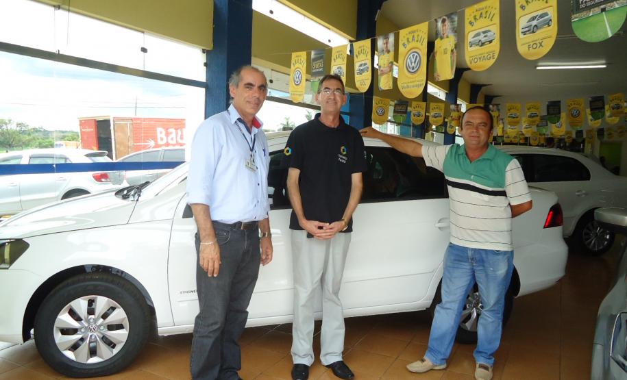 Agente de crédito Reinaldo Ribeiro acompanha os taxistas Estevan Cezar de Oliveira e Rosinei Veronez de Aguiar ao receberem as chaves dos novos veículos.