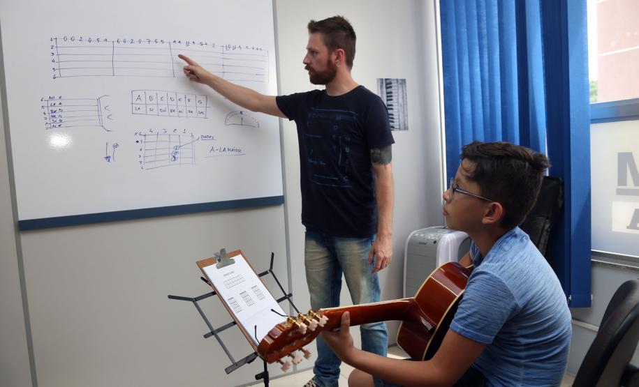 O professor Rodrigo Haniskievicz orienta o aluno Alexandre Pinheiro Neto. Local atende estudantes de música de todas as idades. Empreendedor usou a linha da Fomento Paraná, desenvolvida em parceria com a Secretaria de Estado da Cultura para apoiar empreendimentos da economia criativa.