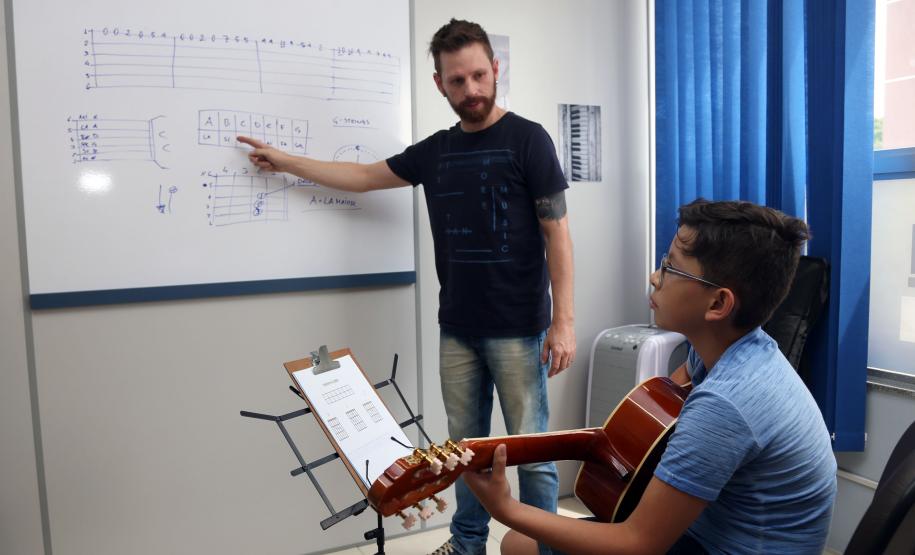 O professor Rodrigo Haniskievicz orienta o aluno Alexandre Pinheiro Neto. Local atende estudantes de música de todas as idades. Empreendedor usou a linha da Fomento Paraná, desenvolvida em parceria com a Secretaria de Estado da Cultura para apoiar empreendimentos da economia criativa.