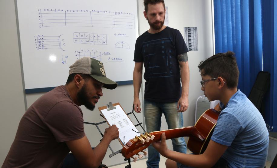 Os professores Rodrigo Haniskievicz (em pé) e Webis Duarte orientam o aluno Alexandre Pinheiro Neto. Local atende estudantes de música de todas as idades. Empreendedor usou a linha da Fomento Paraná, desenvolvida em parceria com a Secretaria de Estado da Cultura para apoiar empreendimentos da economia criativa.