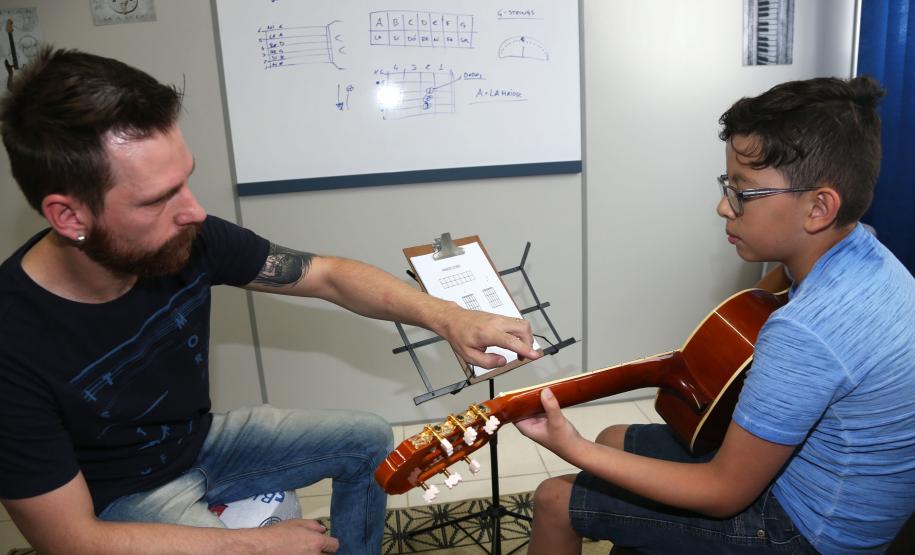 O professor Rodrigo Haniskievicz orienta o aluno Alexandre Pinheiro Neto. Local atende estudantes de música de todas as idades. Empreendedor usou a linha da Fomento Paraná, desenvolvida em parceria com a Secretaria de Estado da Cultura para apoiar empreendimentos da economia criativa.