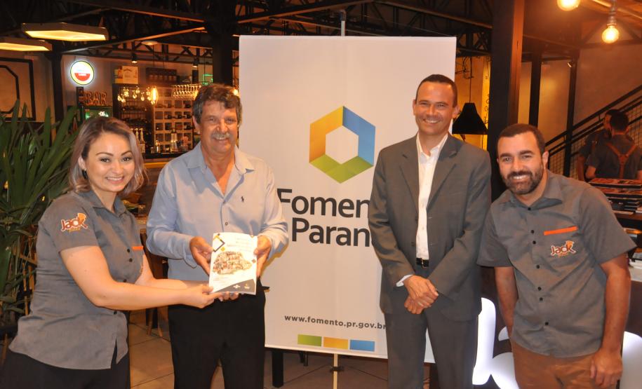 Os empreendedores Elton e Gleide Antunes buscaram dois financiamentos da Fomento Paraná. Passaram de três para 40 funcionários. Hoje vendem mais de 5 mil pizzas por mês. 
Eles receberam um exemplar do livro "O microcrédito melhorando o ambiente de negócios no Paraná" do agente de crédito Aroldo Bertassoni Biss e do gerente de mercado da Fomento Paraná Richer Matos.